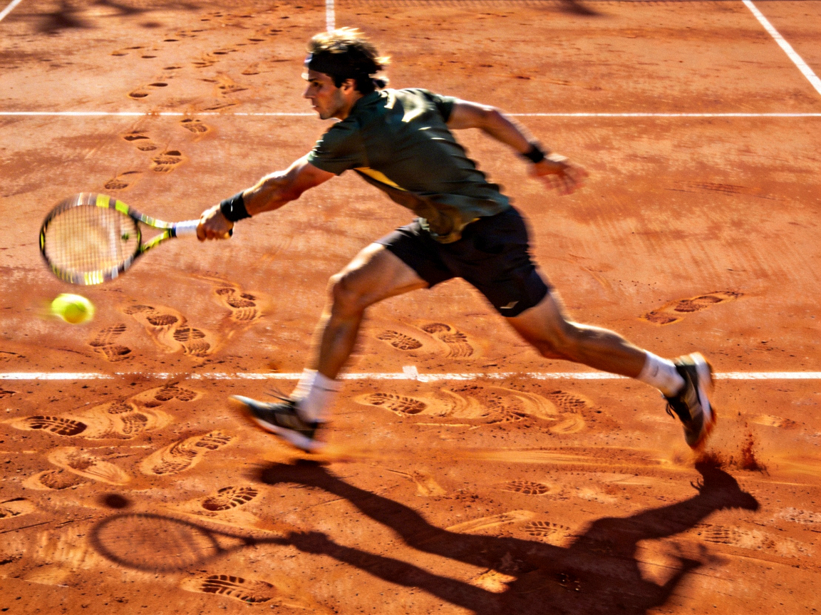 网球运动员在红土场地上奋力奔跑救球的动态瞬间